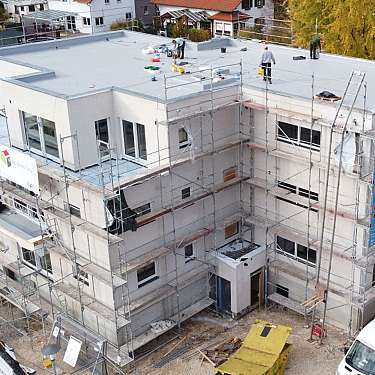 Mehrstöckiges Gebäude mit Baugerüst und Arbeitern auf dem Dach