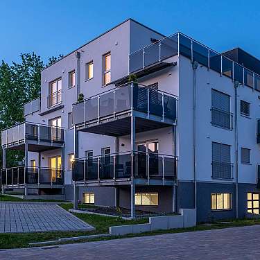 Mehrstöckiges Wohnhaus mit Glasbalkonen bei Dämmerung