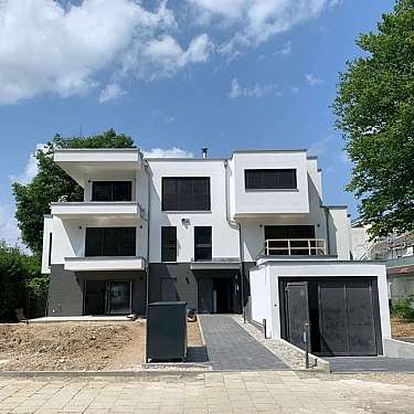 Modernes, weiß-graues Wohnhaus mit großen Fenstern und Zufahrt
