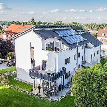 Mehrstöckiges weißes Wohnhaus mit Balkonen und Solarmodulen auf dem Dach