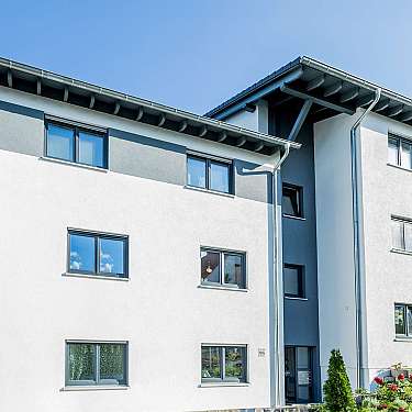 Modernes mehrstöckiges Wohnhaus mit weißen Fassaden und blauem Himmel.