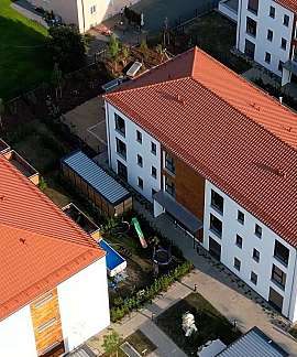 Luftaufnahme mehrerer Wohngebäude mit roten Dächern und Innenhof